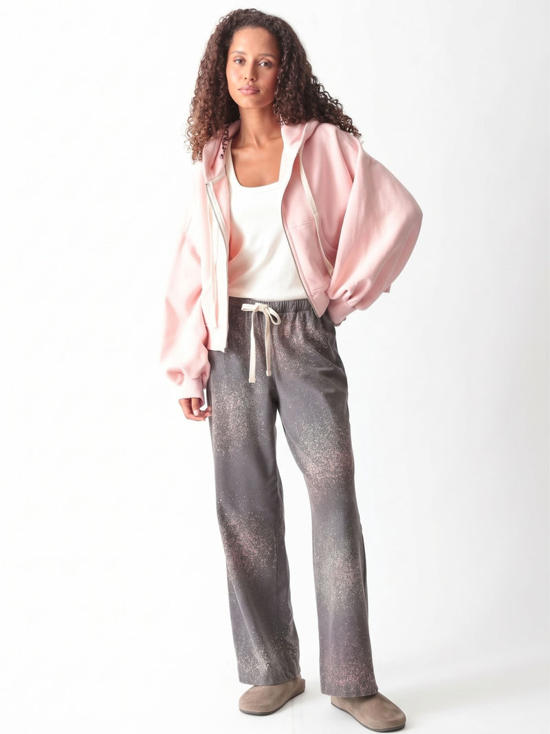 Woman wearing a charcoal gray oversized V-neck French terry sweatshirt with a pink and sage speckled dye print and matching wide-leg sweatpants by Electric & Rose