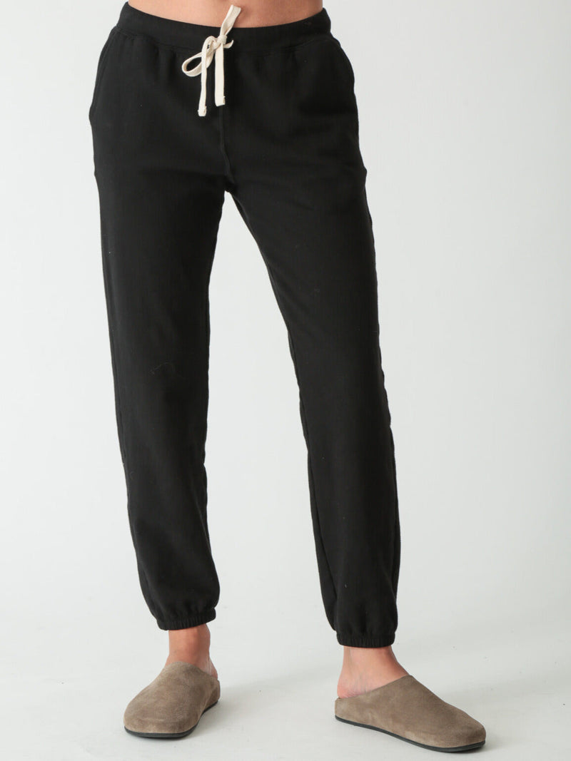 Women wearing a black jogger sweatpants against a white background. 