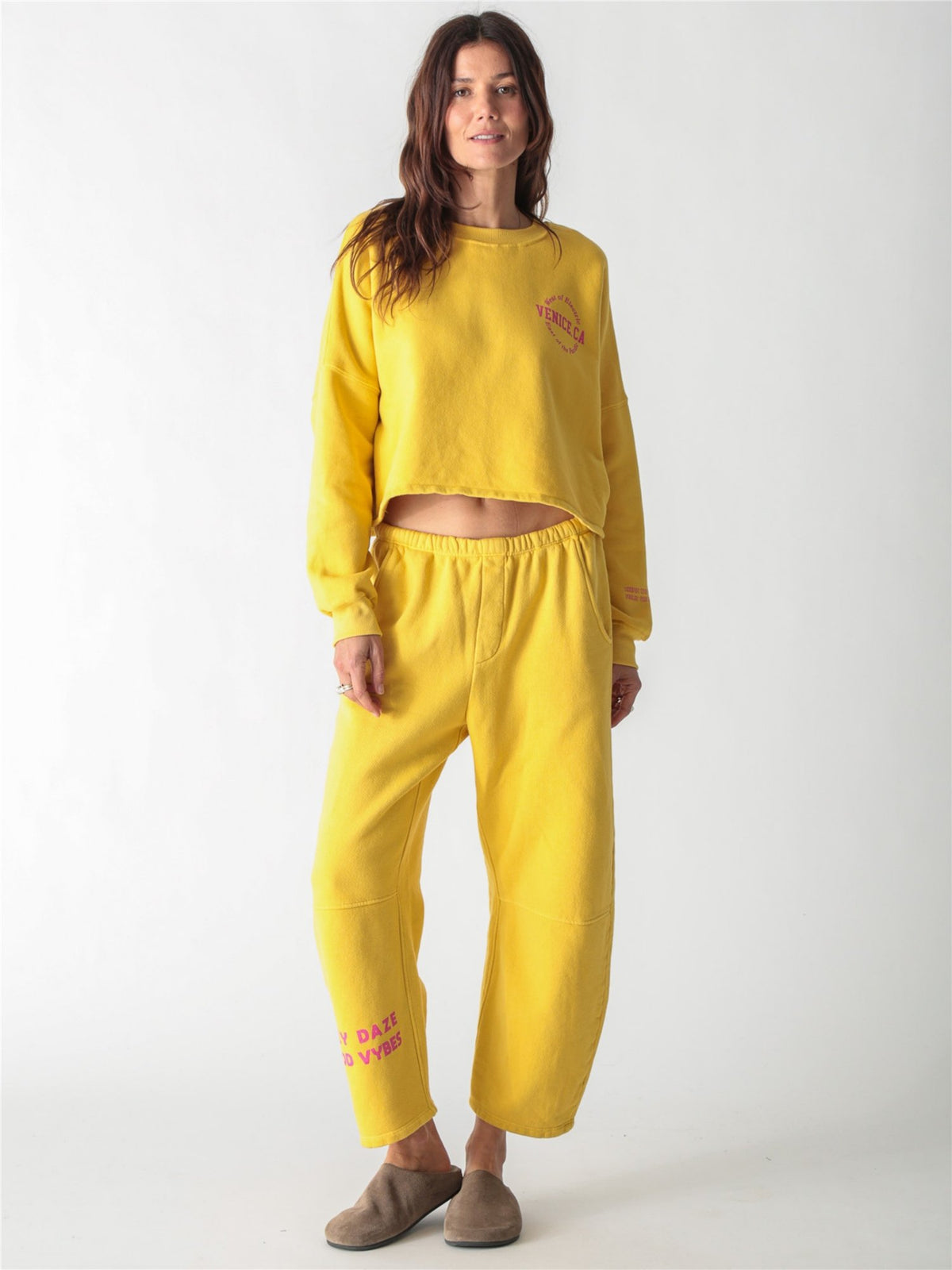 Yellow wide-leg fleece sweatpants featuring an elastic waistband, side pockets, and knee panel seam details.