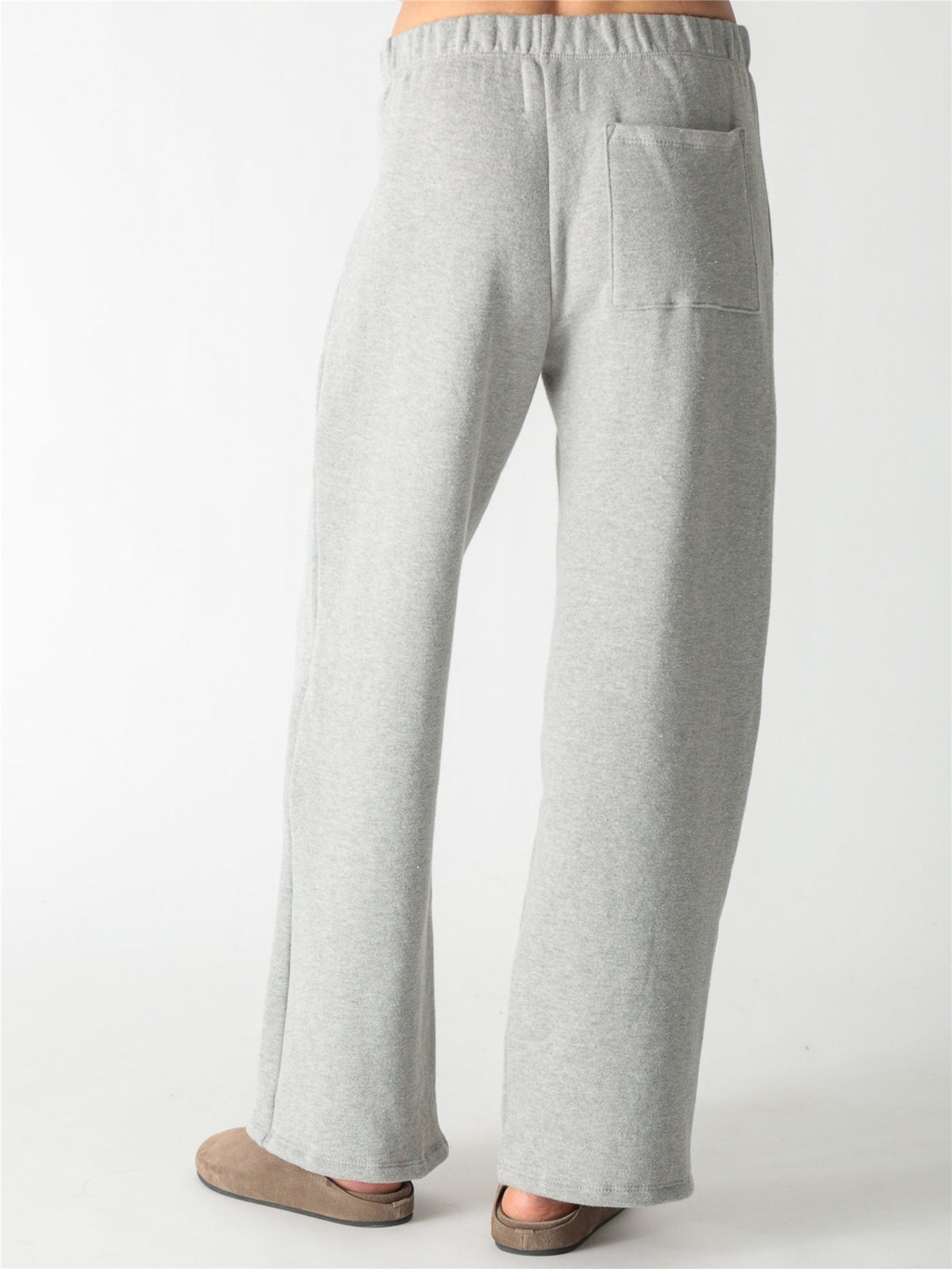 A woman wearing a heather gray cropped zip-up hoodie with voluminous sleeves and matching wide-leg sweatpants against a white background.