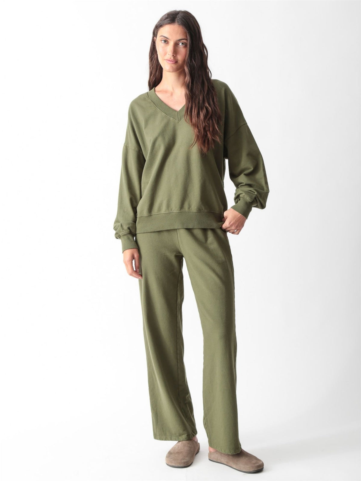 Woman wearing an olive green oversized V-neck sweatshirt with balloon sleeves and matching wide-leg sweatpants by Electric & Rose