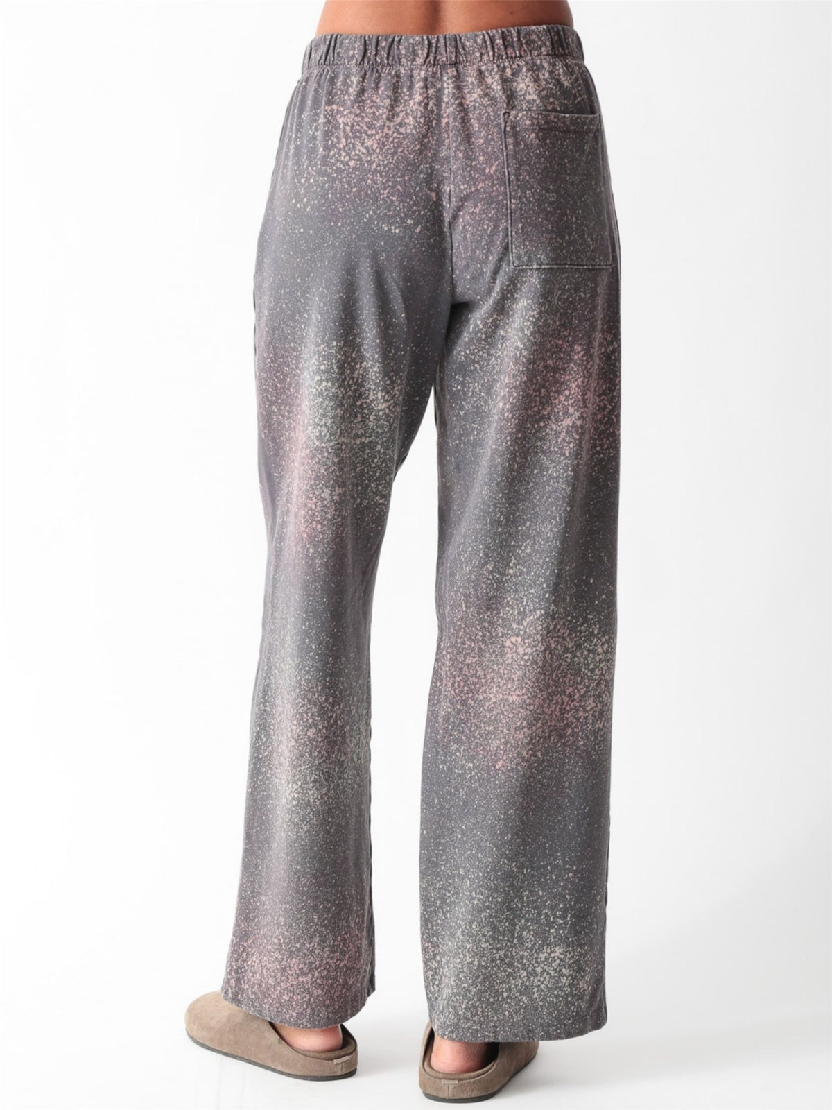 Woman wearing a charcoal gray oversized V-neck French terry sweatshirt with a pink and sage speckled dye print and matching wide-leg sweatpants by Electric & Rose