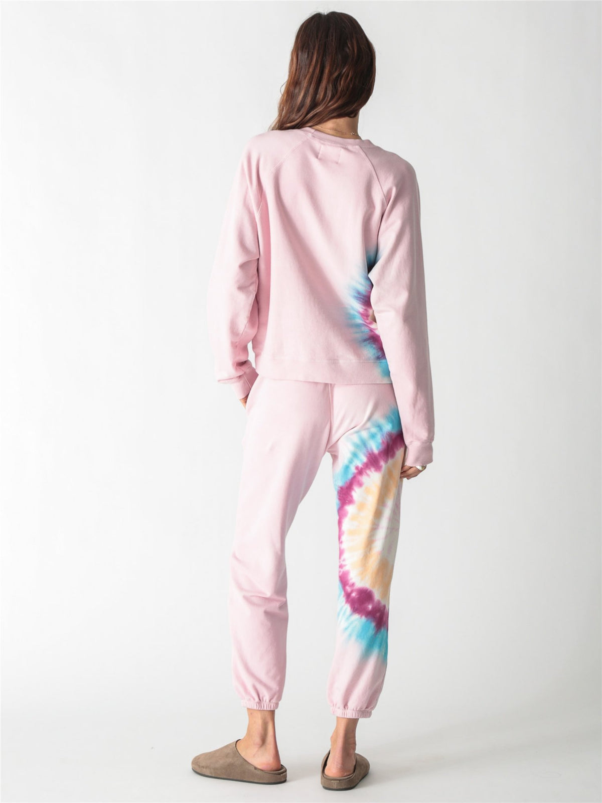 A light pink crewneck sweatshirt with long sleeves, ribbed trim, and a colorful tie-dye stripe down the right side.