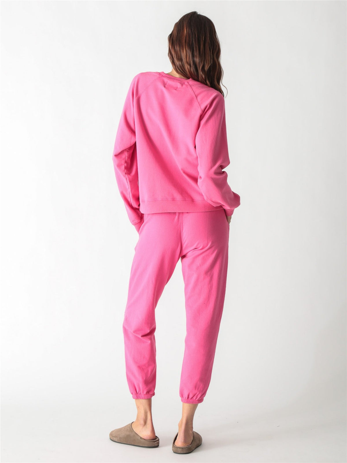 Bright pink crewneck sweatshirt featuring a small pale pink palm tree graphic on the left chest.
