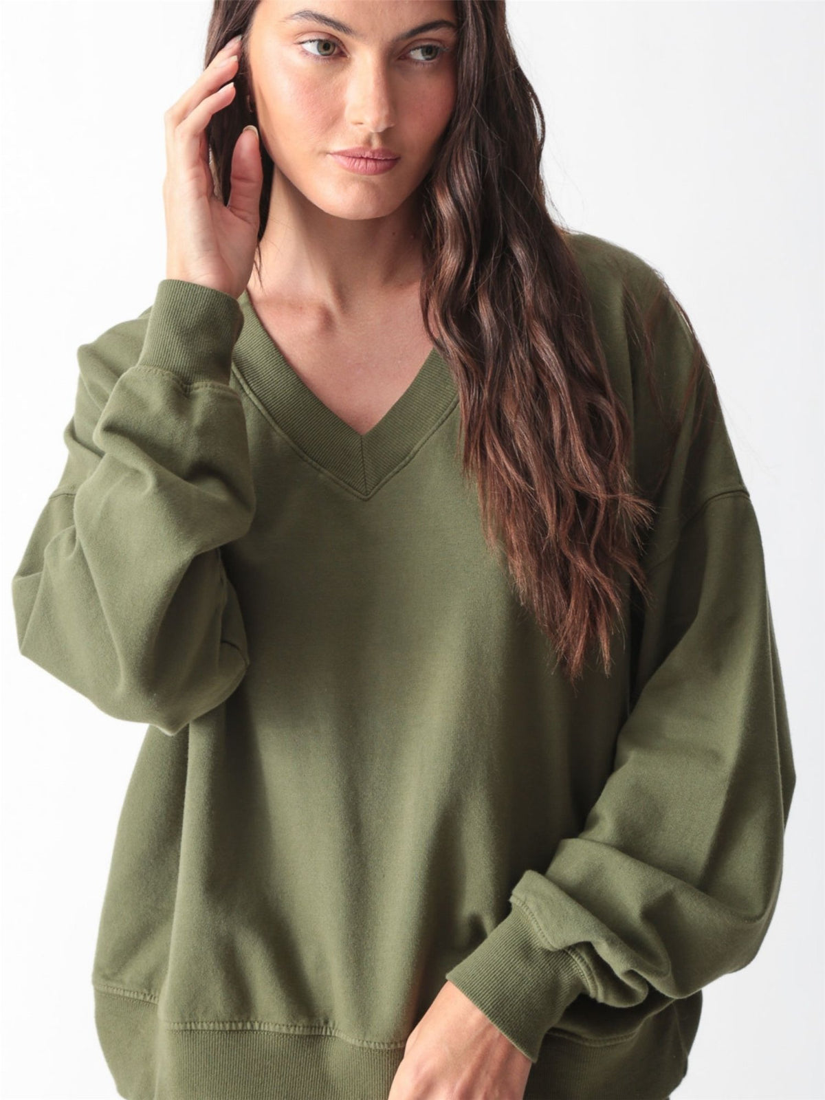 Woman wearing an olive green oversized V-neck sweatshirt with balloon sleeves and matching wide-leg sweatpants by Electric & Rose