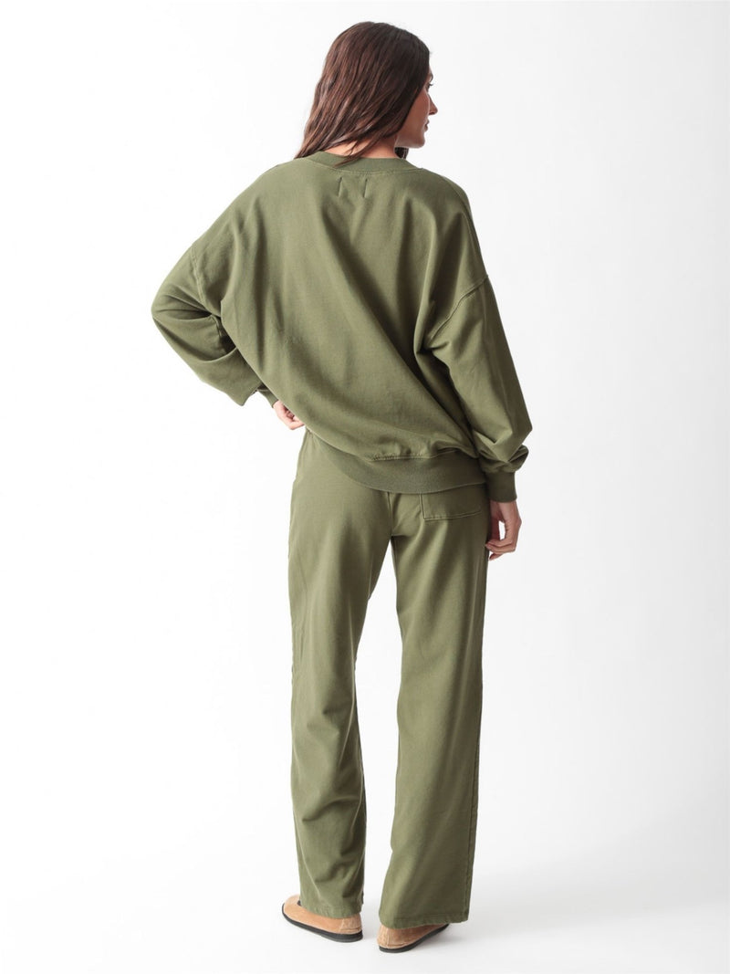 Woman wearing an olive green oversized V-neck sweatshirt with balloon sleeves and matching wide-leg sweatpants by Electric & Rose