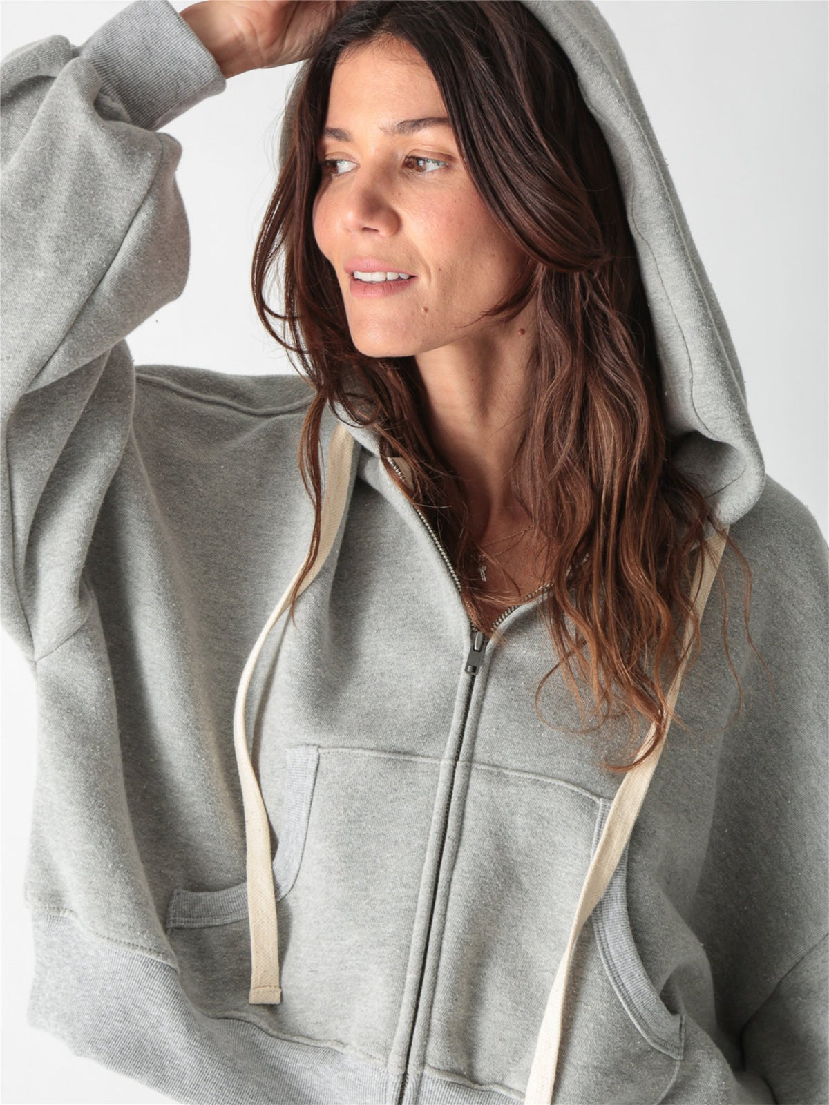 A woman wearing a heather gray cropped zip-up hoodie with voluminous sleeves and matching wide-leg sweatpants against a white background.