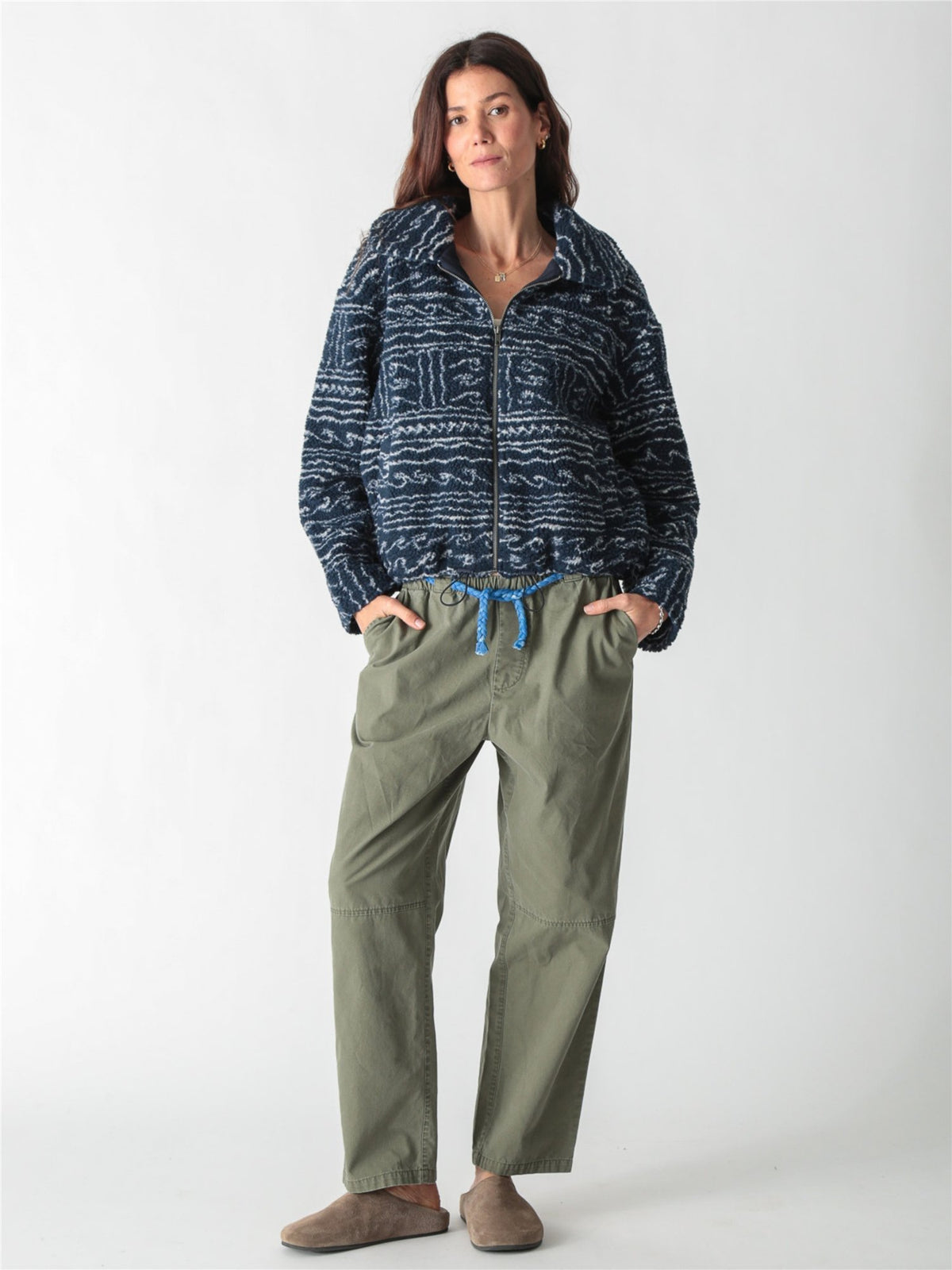 A woman wearing a dark blue and white patterned fleece zip-up jacket paired with drawstring denim jeans against a plain white background.
