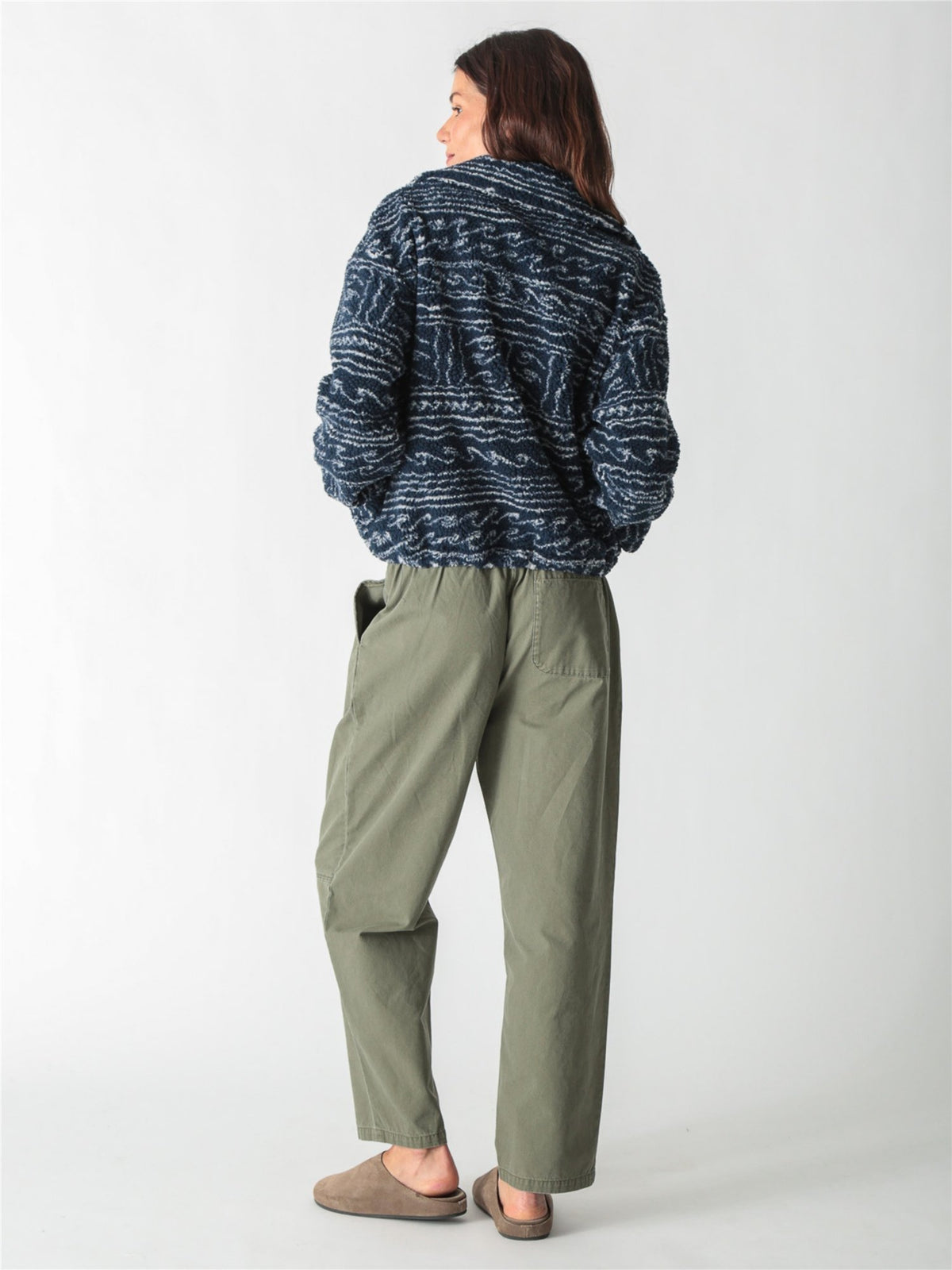 A woman wearing a dark blue and white patterned fleece zip-up jacket paired with drawstring denim jeans against a plain white background.