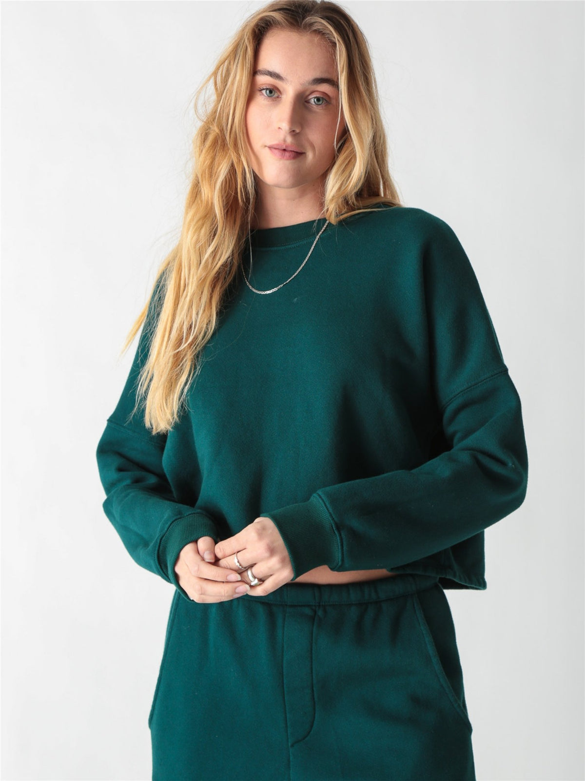 A dark teal green oversized cropped crewneck sweatshirt with dropped shoulders and ribbed cuffs.