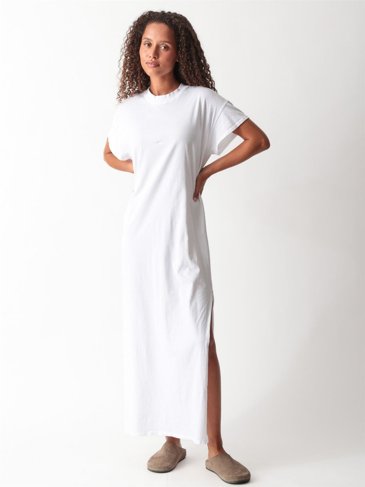 Woman wearing a white cotton jersey maxi T-shirt dress with short cuffed sleeves, crew neck, and side slit by Electric & Rose