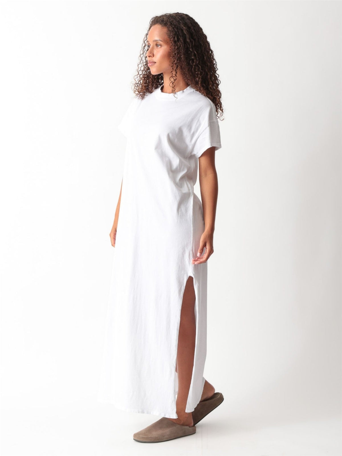 Woman wearing a white cotton jersey maxi T-shirt dress with short cuffed sleeves, crew neck, and side slit by Electric & Rose