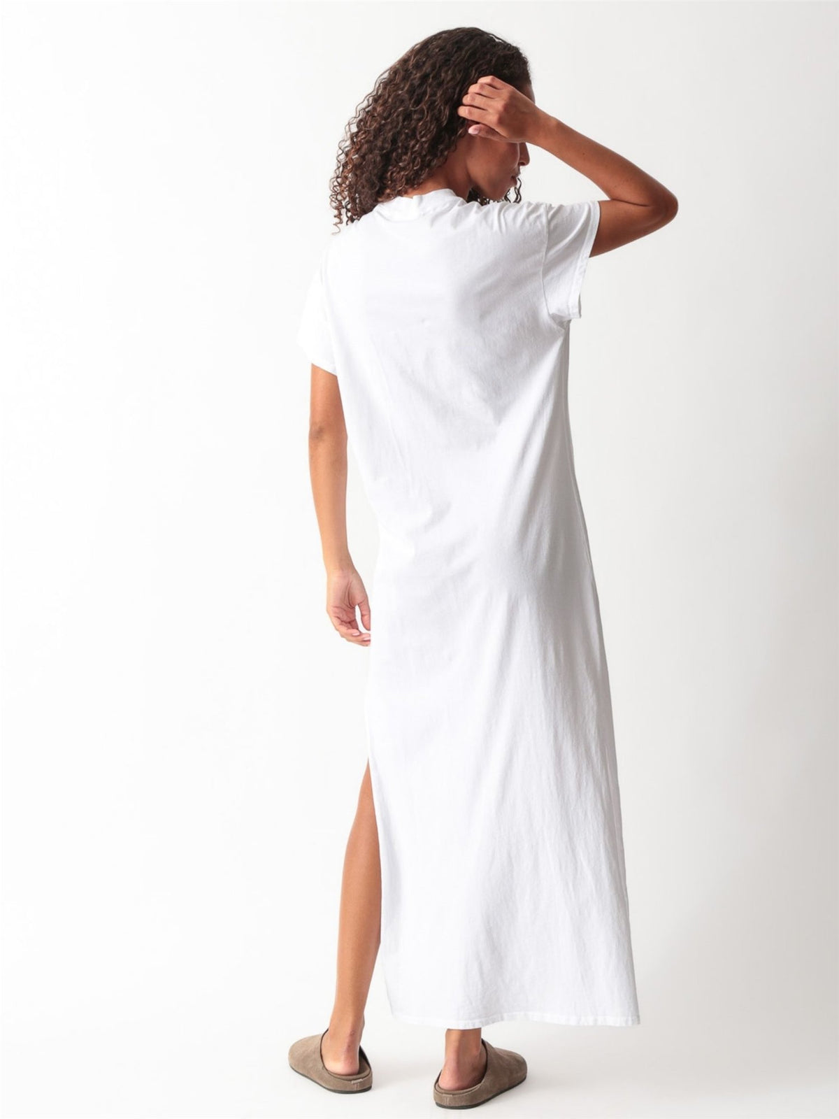 Woman wearing a white cotton jersey maxi T-shirt dress with short cuffed sleeves, crew neck, and side slit by Electric & Rose
