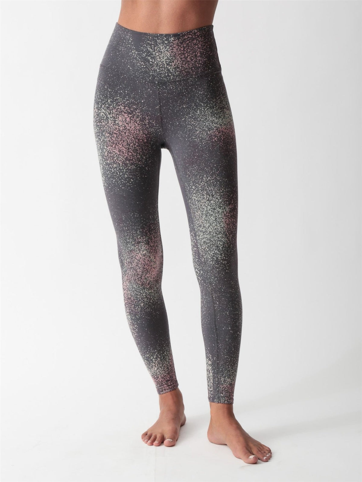 Woman wearing a charcoal gray scoop-neck sports bra and matching high-waisted leggings with a pink and sage speckled print by Electric & Rose