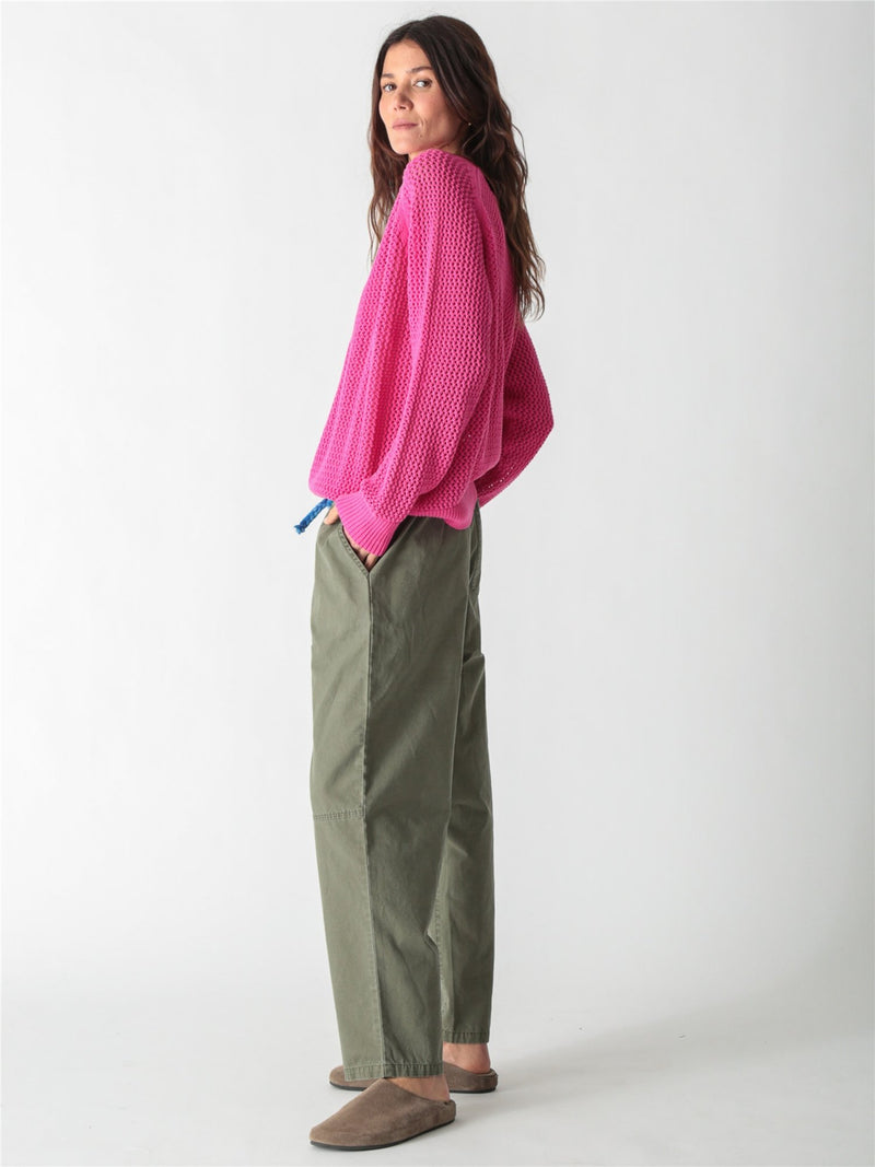 Bright pink open-knit crewneck sweater with long wide sleeves and ribbed cuffs.