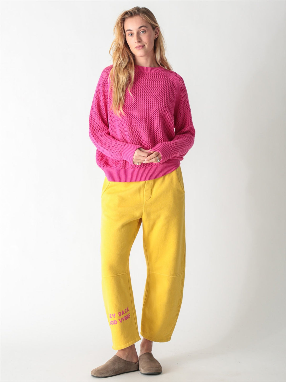 Bright pink open-knit crewneck sweater with long wide sleeves and ribbed cuffs.