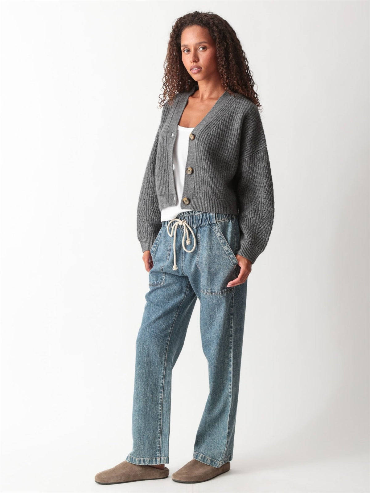 Close-up of a heather gray ribbed-knit cropped V-neck cardigan with tortoiseshell buttons, styled with drawstring denim, by Electric & Rose