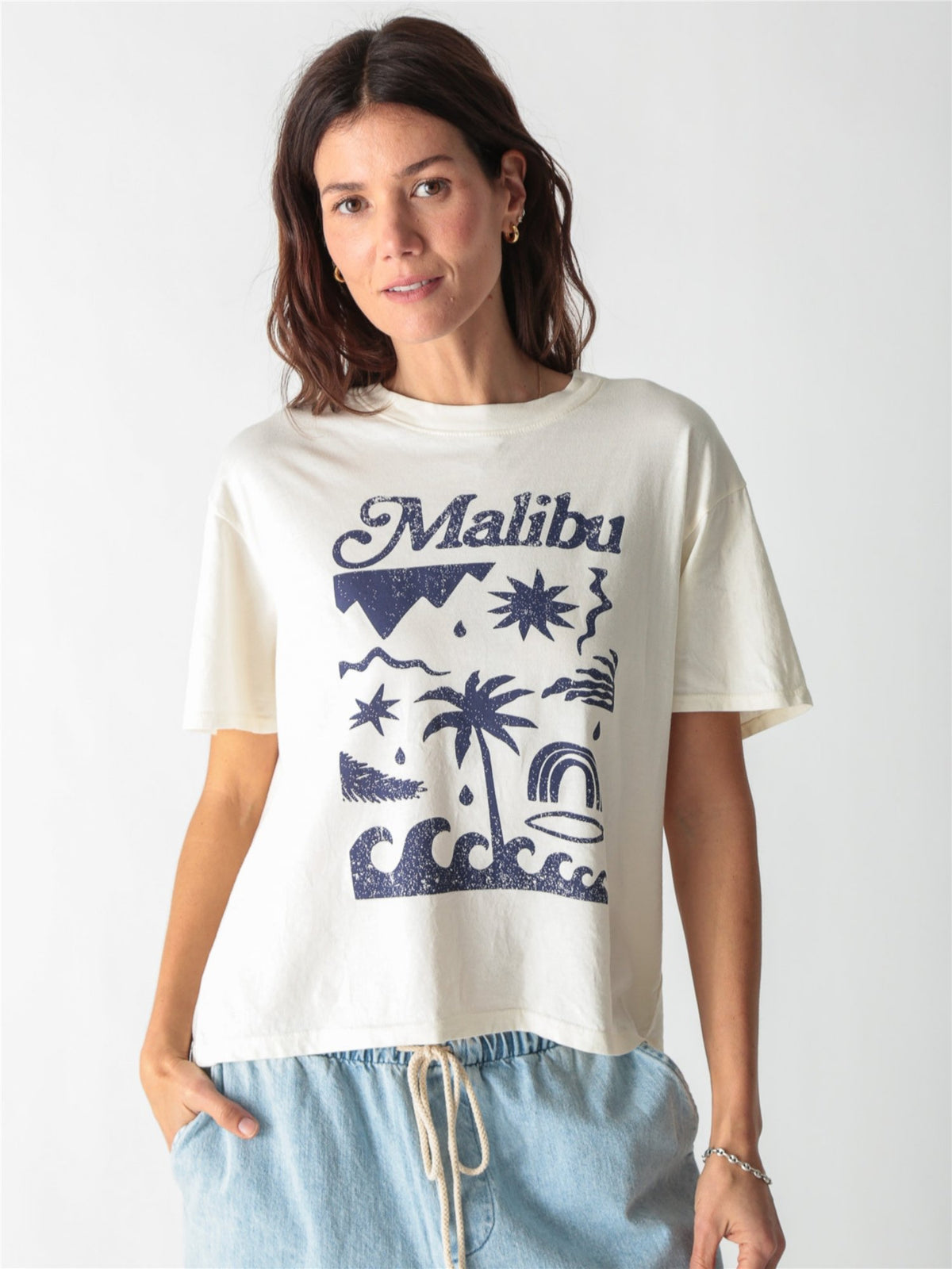 Off-white t-shirt featuring blue "Malibu" script and beach-inspired graphic art printed on the front.