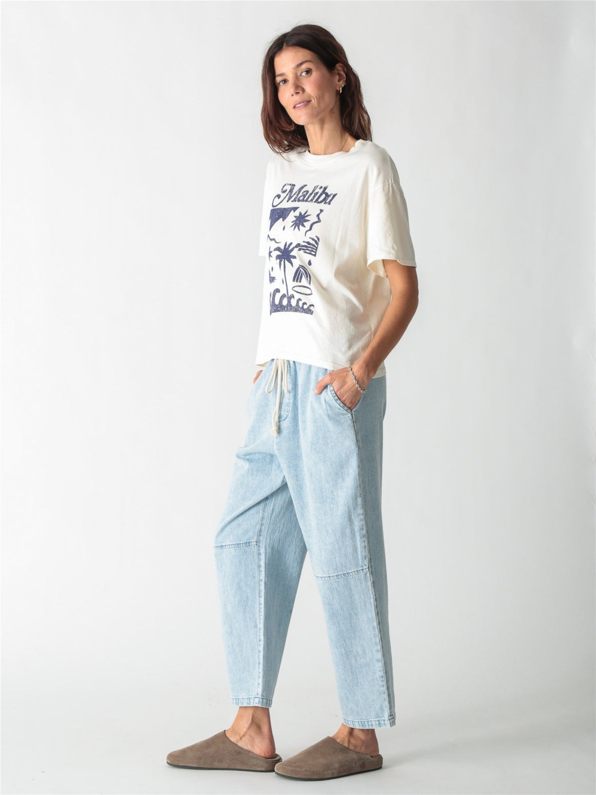 Off-white t-shirt featuring blue "Malibu" script and beach-inspired graphic art printed on the front.